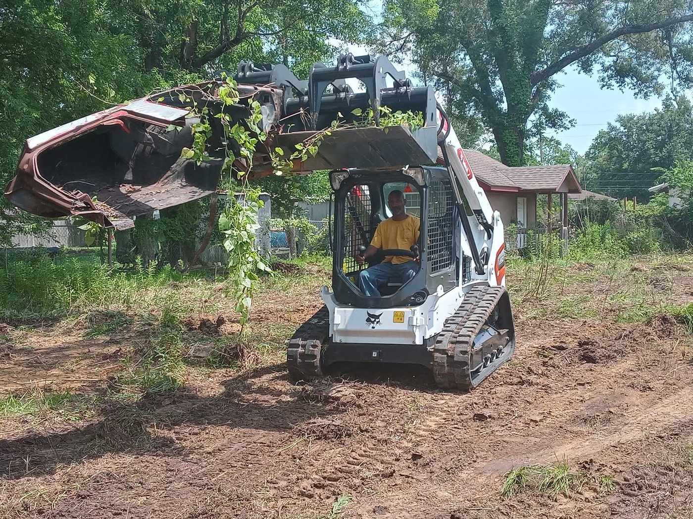 Skid steer clearing overgrown brush on a job site